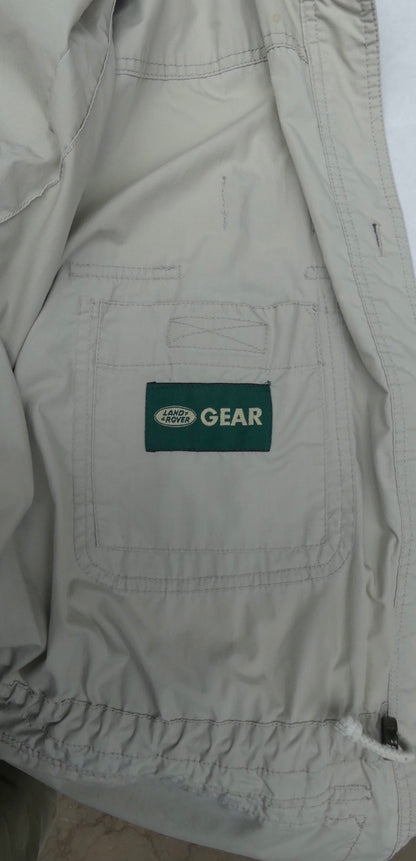 Close-up of a light beige or off-white jacket or overshirt with a green rectangular patch reading 'LAND ROVER GEAR' on the chest pocket.
