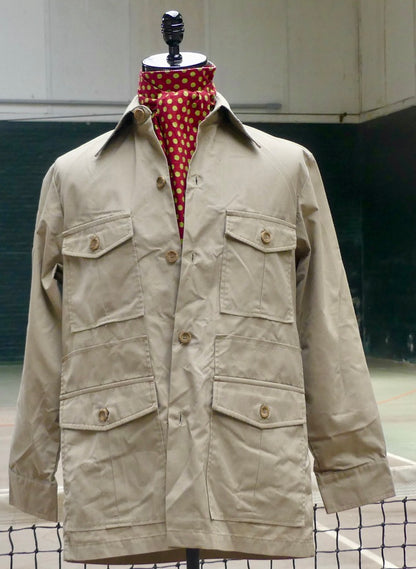 A beige utility jacket with four front flap pockets and brown buttons, displayed on a mannequin torso with a red and white polka dot neck scarf.