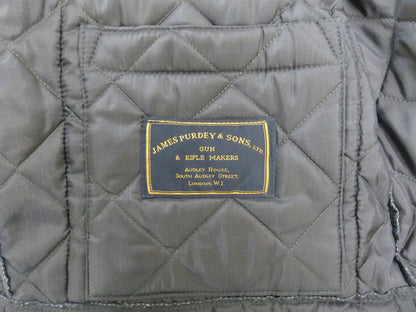 Close-up of a quilted gray fabric jacket interior with a central black brand patch reading James Purdy & Sons.