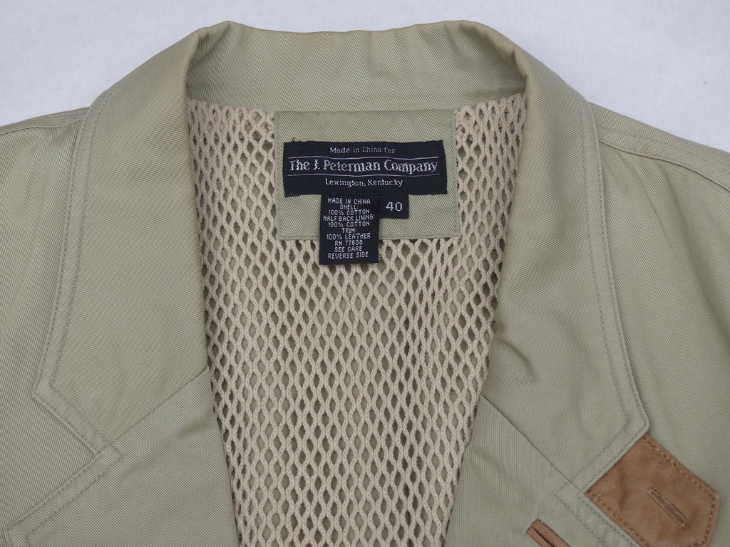 Close-up of the collar and inner neck of a vintage olive green jacket by The 1. Peterman Company, showing a beige mesh lining and a black brand label.