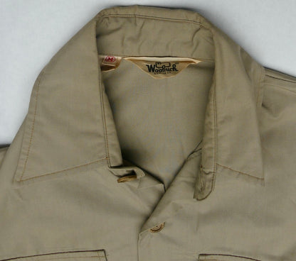 A close-up of a khaki beige button-up shirt collar, showing the interior neck label which reads 'Woolrich'