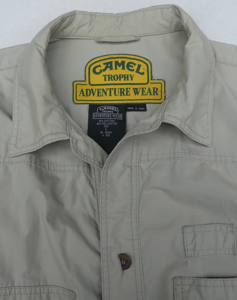 Close-up of a light khaki Camel Trophy Adventure Wear button-up shirt showing the inner collar label and chest pocket.